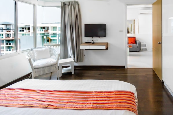 A hotel room with a bed, a TV, a chair, and a view of the city.