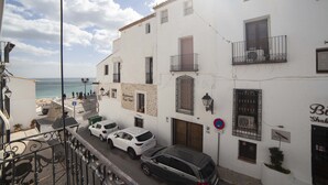 A narrow street with white buildings, a beach in the background, and parked cars. - Apartment 43m2 sea view (Altea)