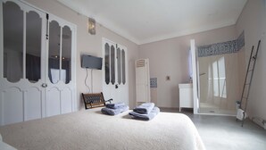 A bedroom with a large bed, a TV mounted on the wall, and a bathroom visible through an open door. - Apartment 43m2 sea view (Altea)