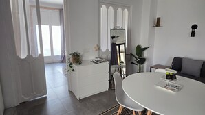 A modern, well-lit room with a round dining table, white chairs, a white dresser, and a large mirror. - Apartment 43m2 sea view (Altea)