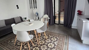 A modern living room with a round dining table, white chairs, a grey sofa, and a patterned rug. - Apartment 43m2 sea view (Altea)