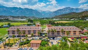 A hotel with multiple floors, a central courtyard, and a view of mountains.