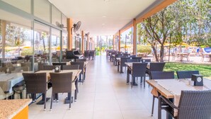 A spacious indoor dining area with multiple tables and chairs, large windows, and ceiling fans.