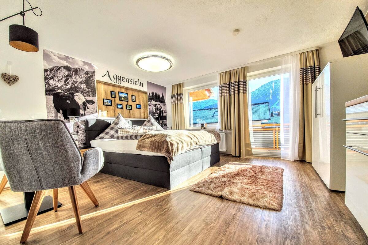 A modern bedroom with a bed, a chair, a rug, and a mural on the wall.