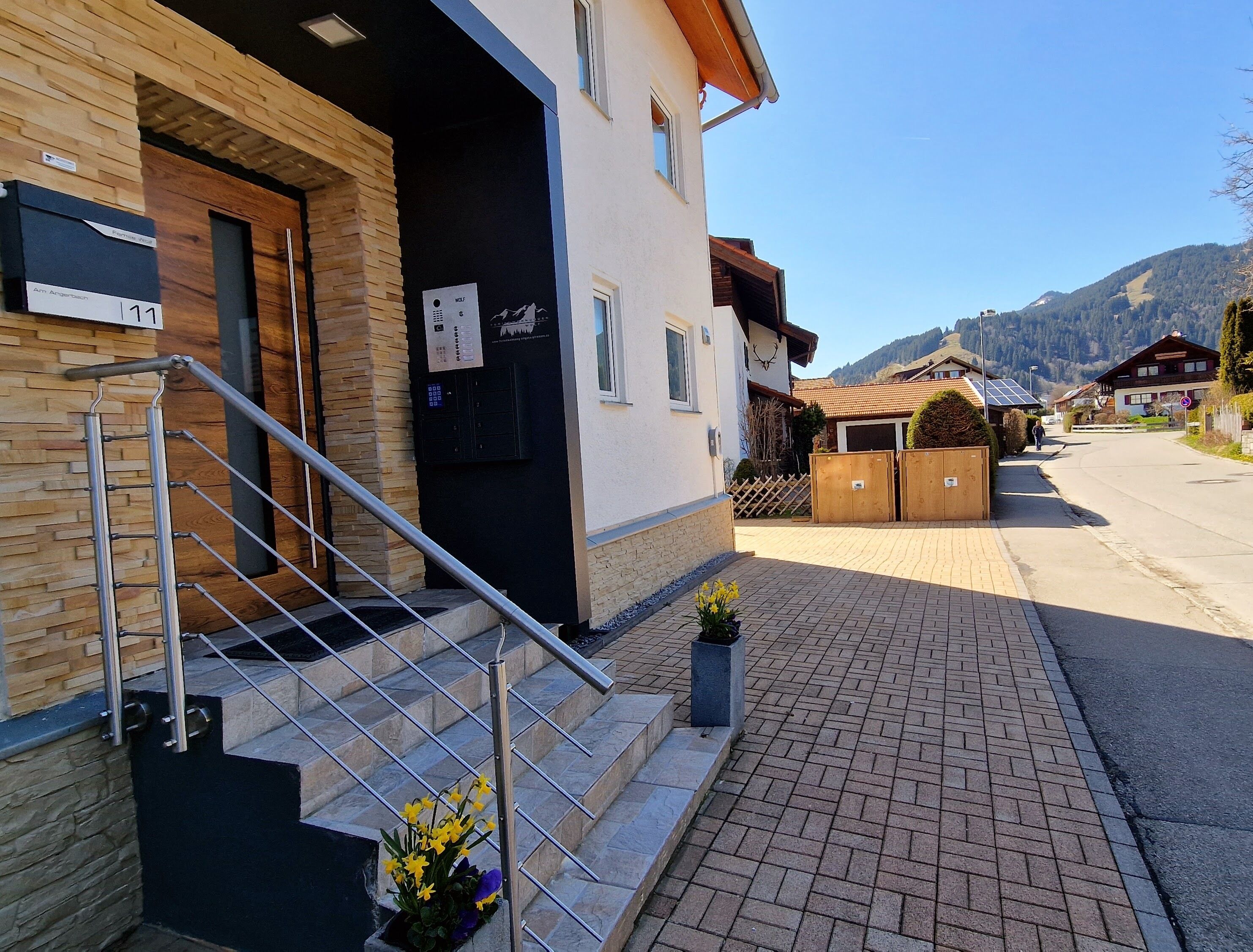 Ein Gebäude mit Holzfassade, einer Treppe mit Metallgeländern und einem gepflasterten Bürgersteig.