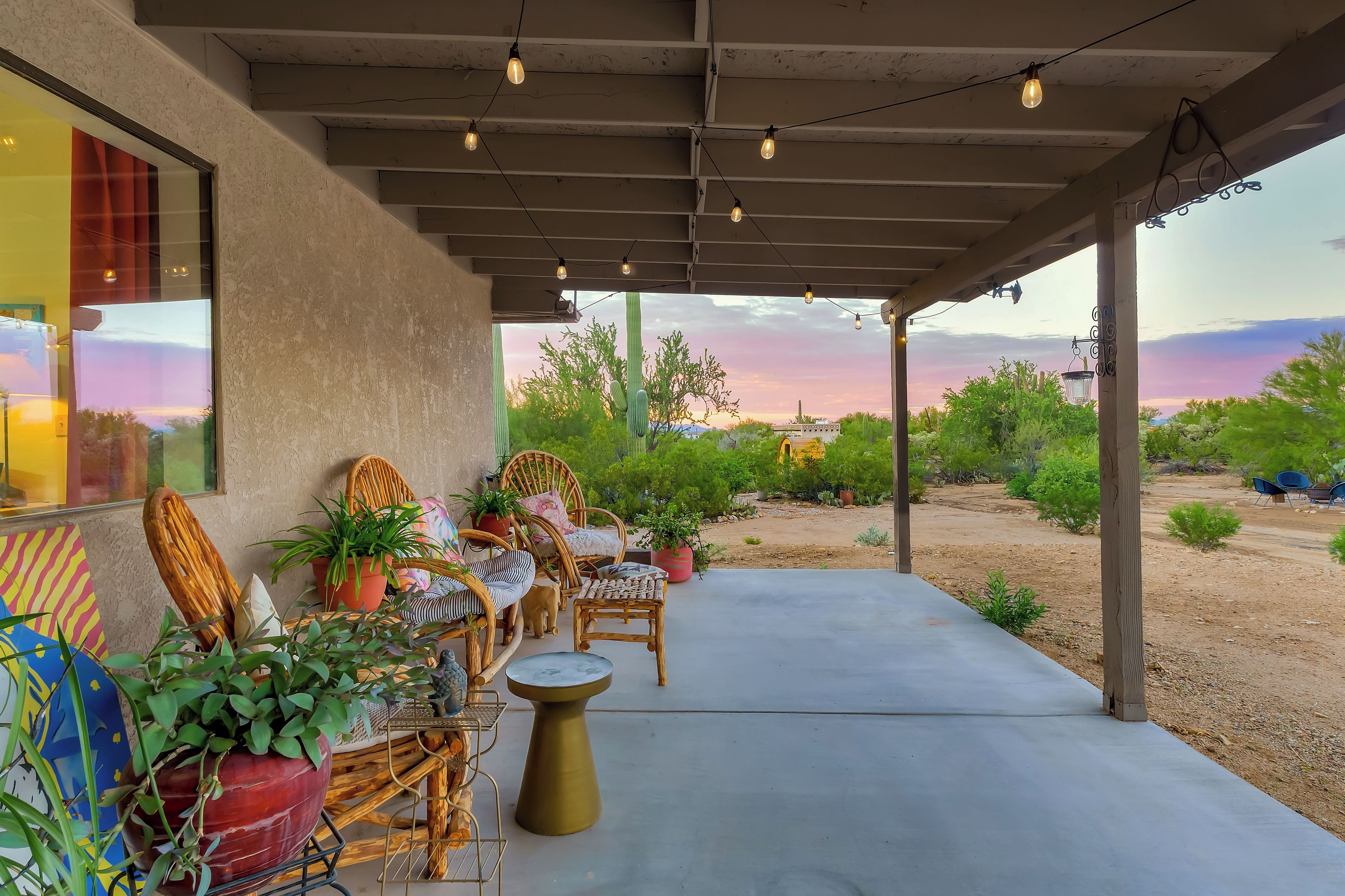 An outdoor patio with seating, potted plants, and a view of the desert landscape.