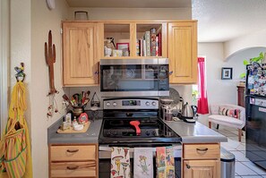 Une cuisine de taille réduite, dotée de meubles en bois, d’un four à micro-ondes, d’une cuisinière et d’un réfrigérateur.
