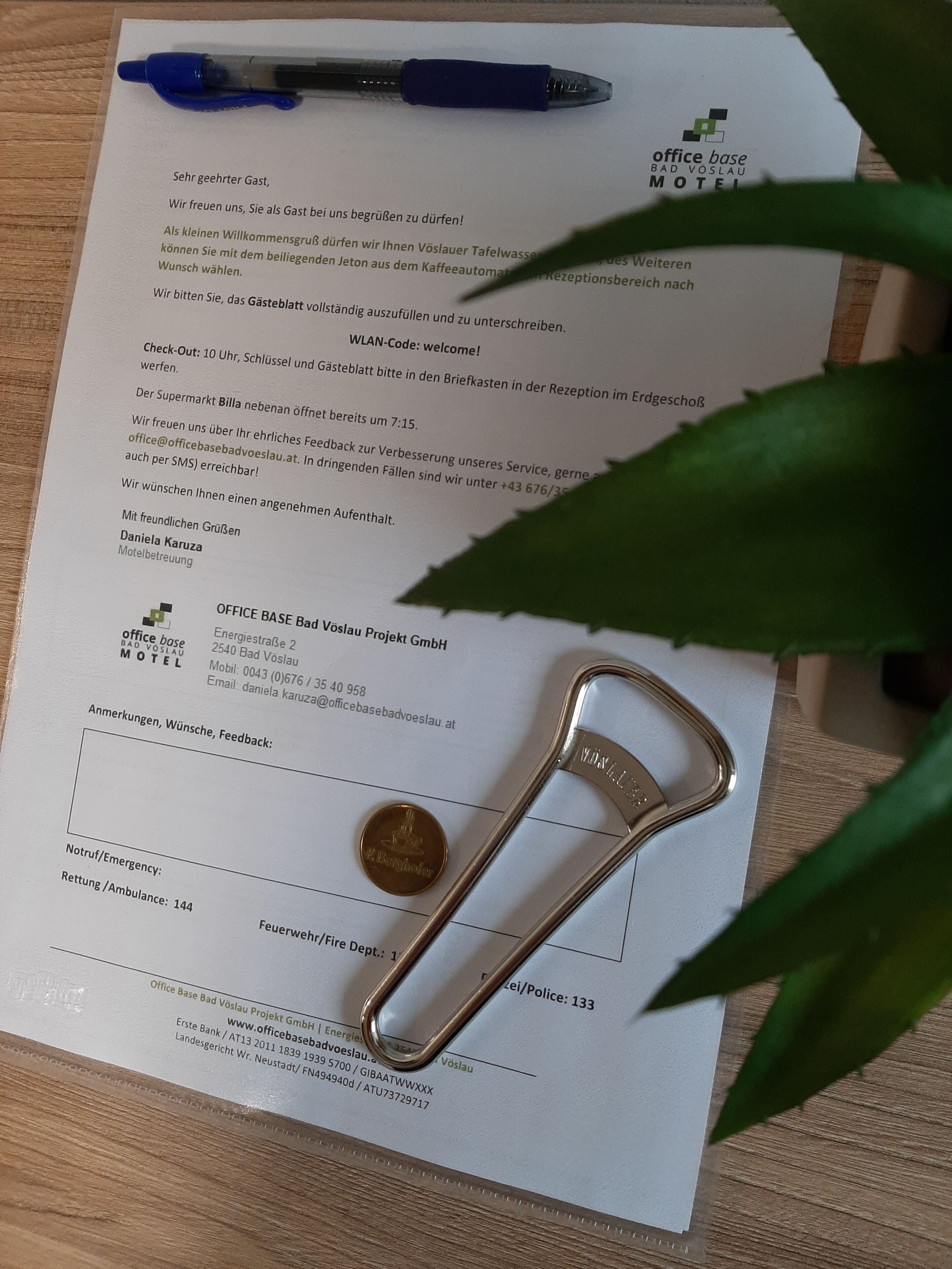 A hotel receipt with a pen, a coin, and a paperclip on a wooden surface.