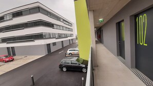 A modern building with a parking area, a red car, and a black car parked. - MOTEL Bad Vöslau (Bad Voeslau)