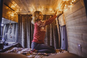 Een kamer met houten wanden, een bed met een geruit plaid en sprookjesachtige lichtjes.