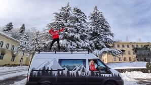 A van parked on a snowy street with a person standing on top and another inside. - Self-built campervan (Kutaisi)