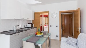 A compact kitchen with white cabinets, a microwave, and a fruit bowl on the counter.