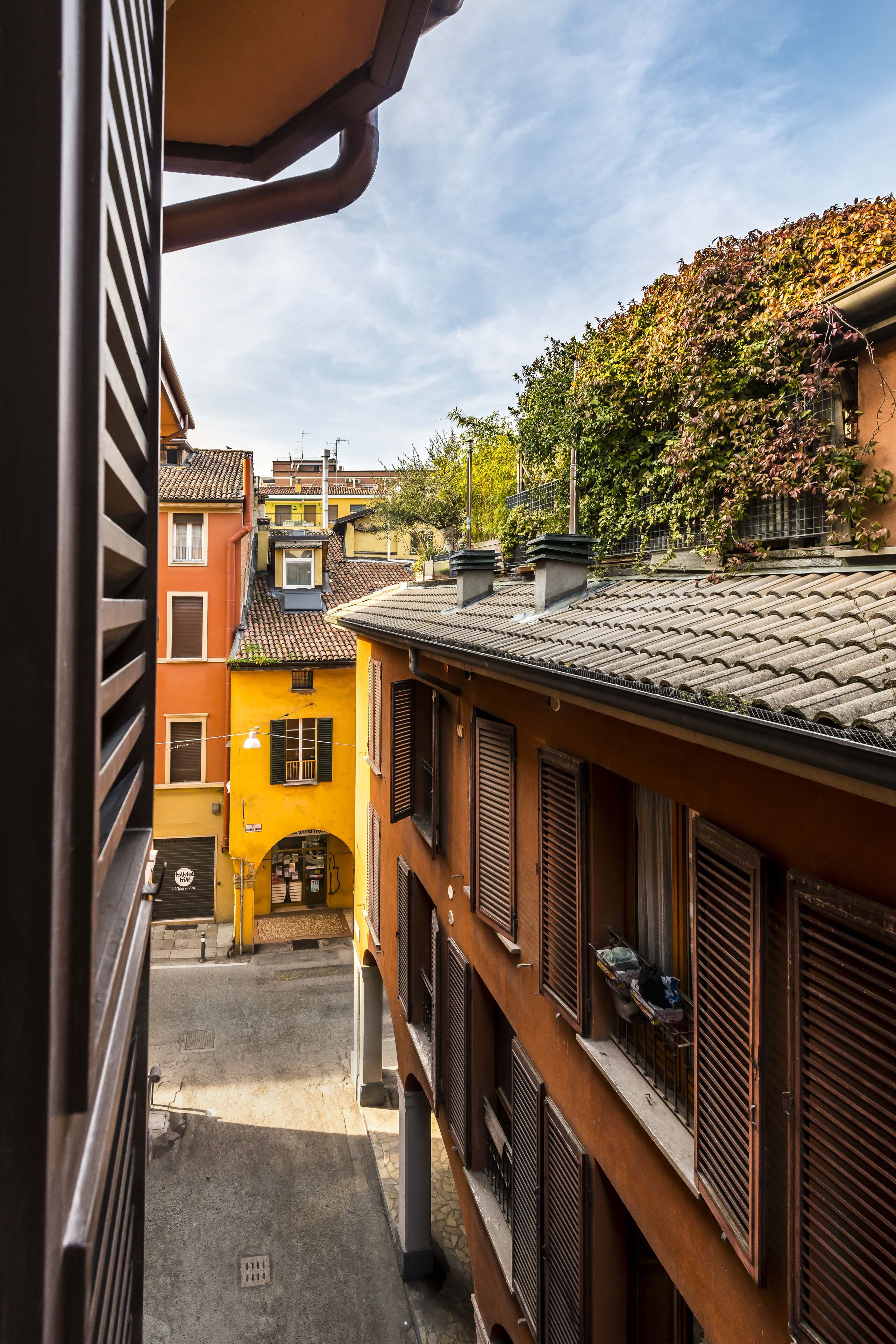 A narrow alleyway between buildings with traditional architecture, including shuttered windows and a tiled roof.