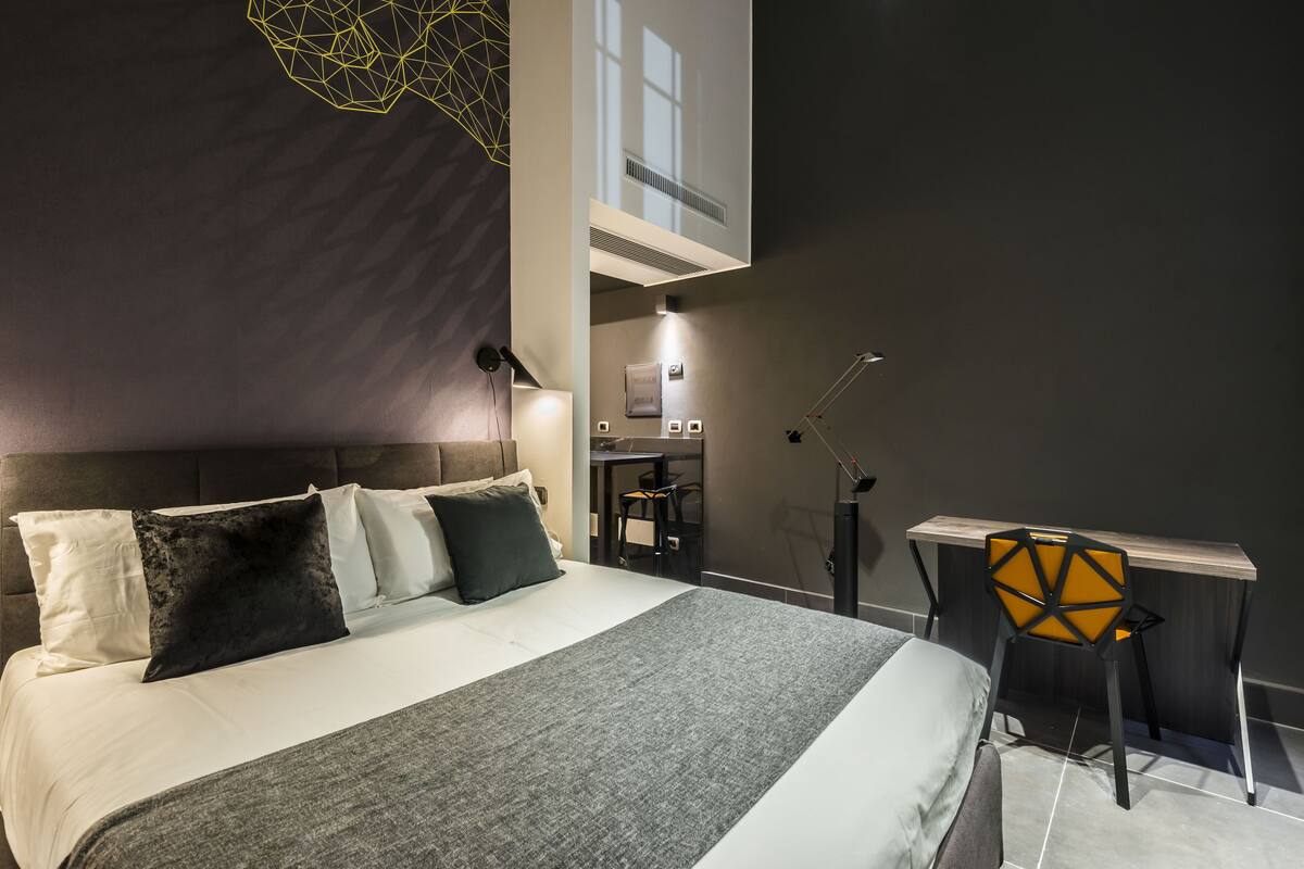 Ein modernes Hotelzimmer mit einem großen Bett, einem Schreibtisch und einem Sessel.