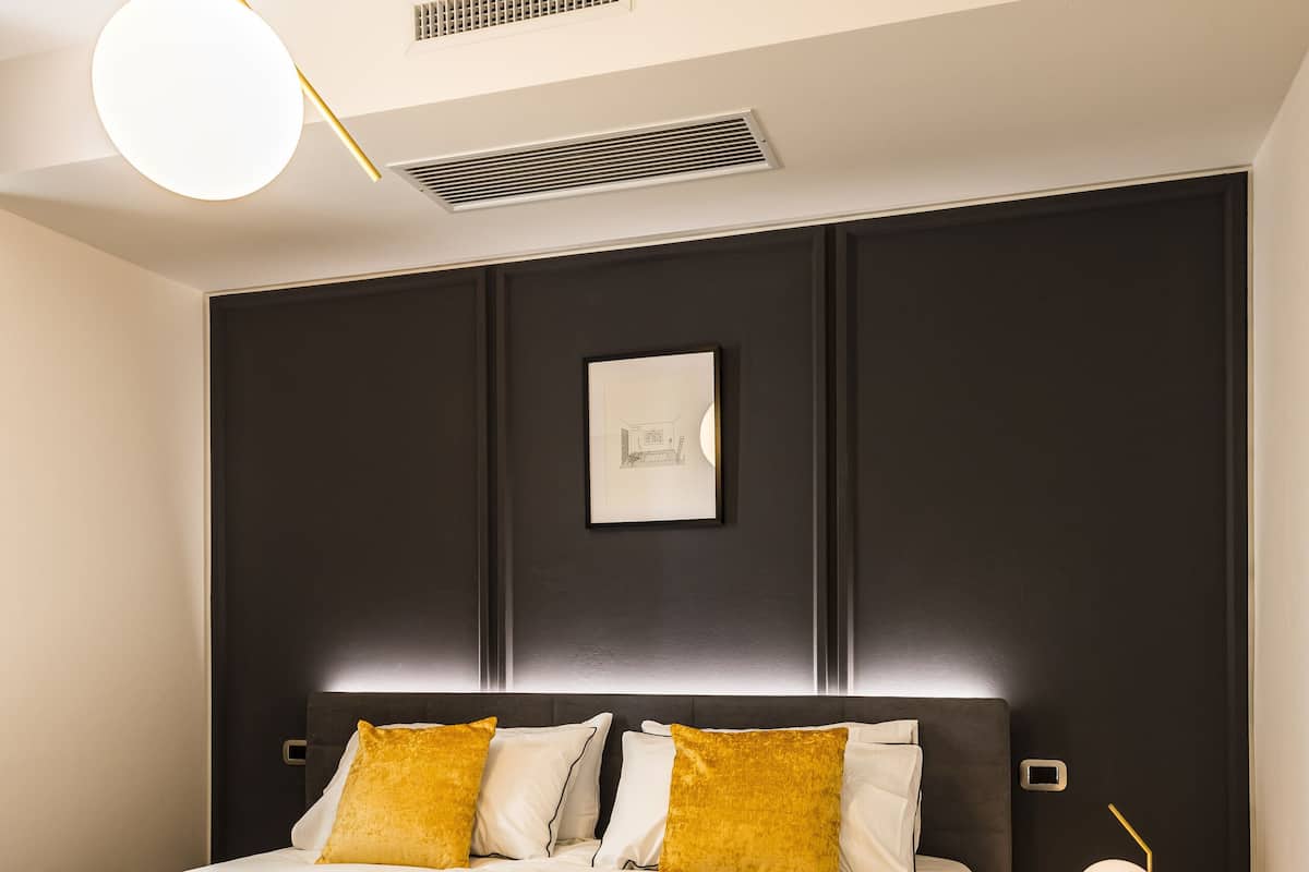 Ein modernes Schlafzimmer mit einem großen Bett, einem Nachttisch mit Lampe und einer Deckenleuchte.