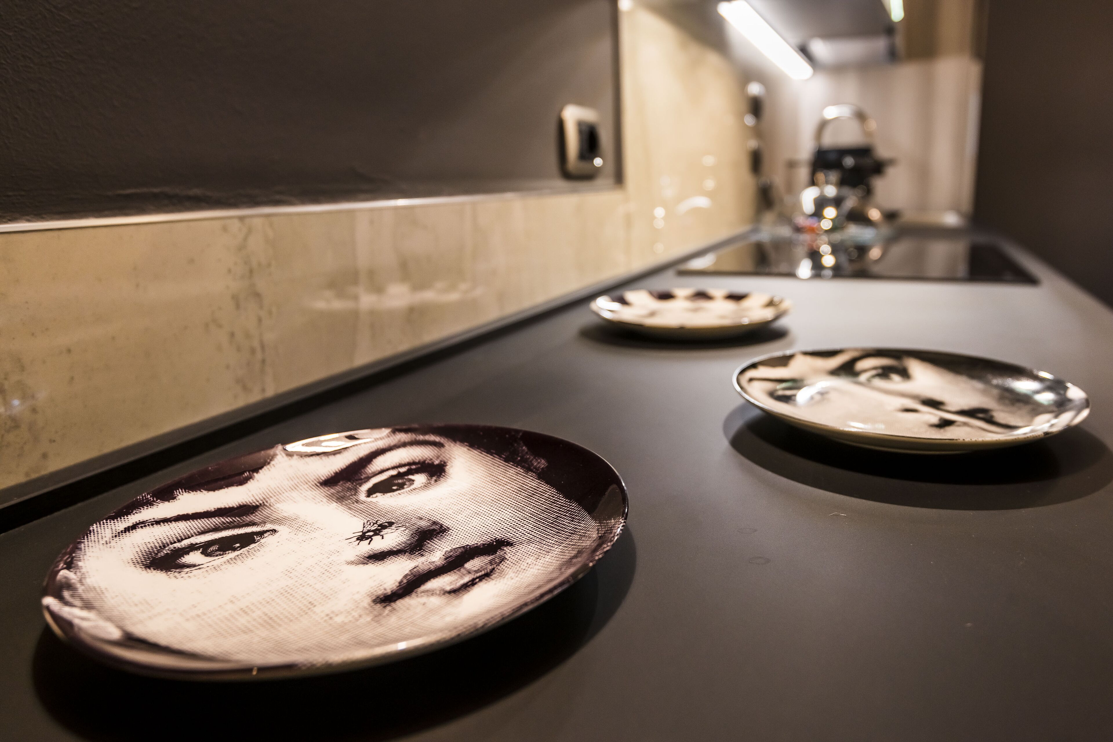 Un baño con un espejo, un lavabo y tres platos con diseños de caras sobre la encimera.