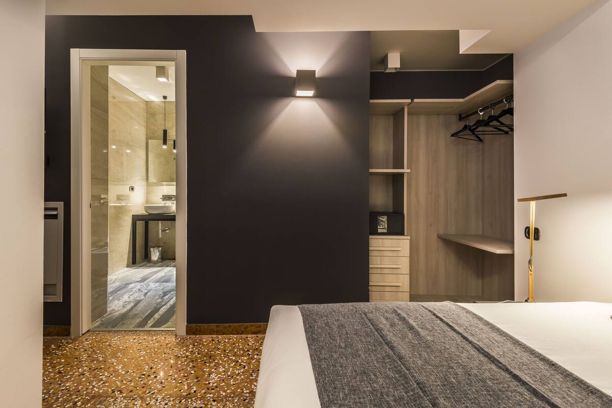 Ein modernes Schlafzimmer mit Bett, begehbarem Kleiderschrank und angrenzendem Badezimmer.