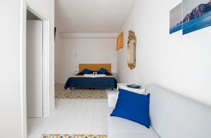 Un dormitorio con una cama, un sofá blanco y una alfombra estampada.