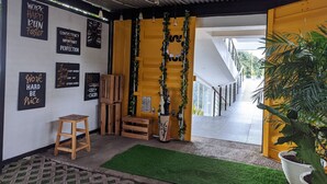 A modern interior with motivational wall art, a wooden stool, and a green artificial turf area. - Terra Cassa Hotel (Bandungan)