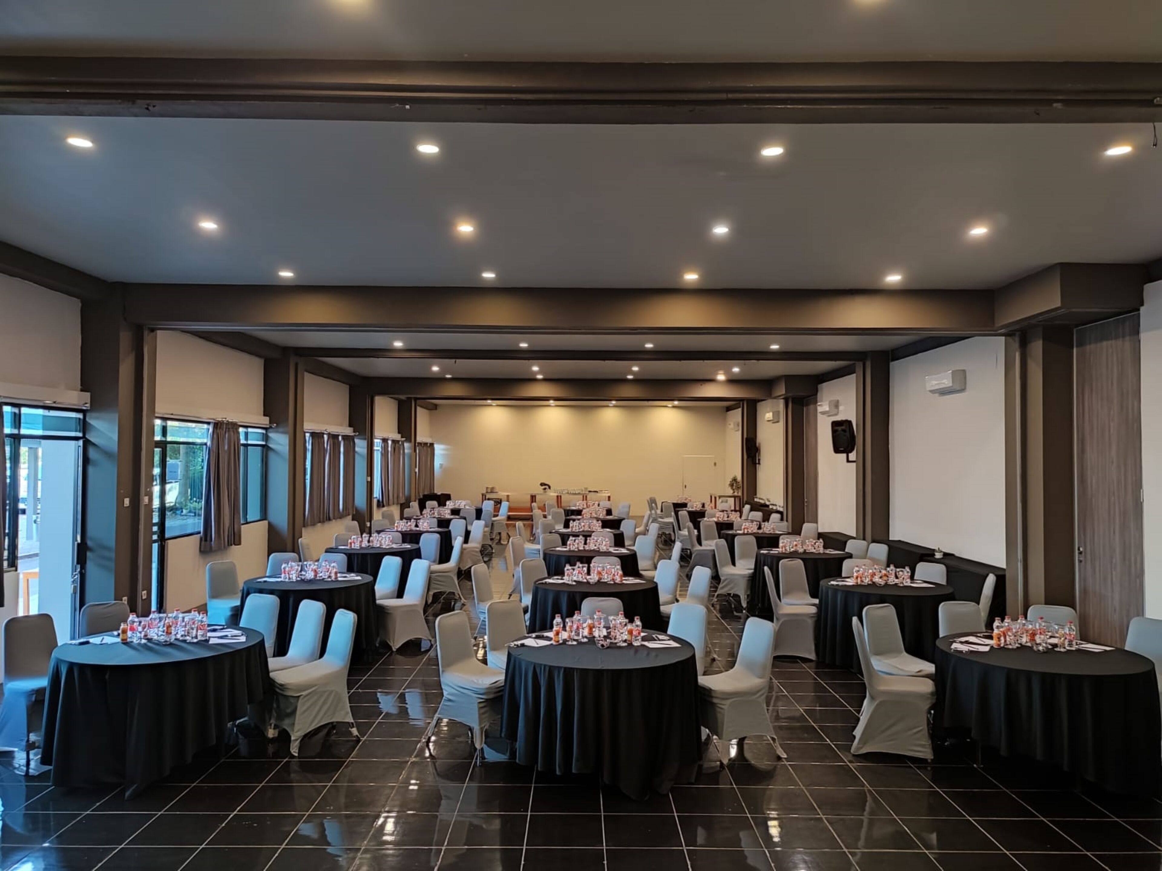 A conference room with round tables, chairs, and a stage.