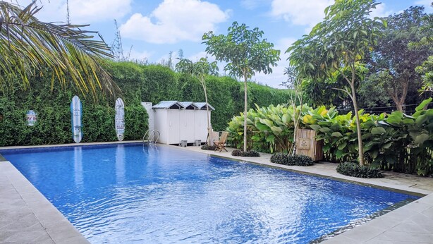 A rectangular swimming pool with a tiled deck, surrounded by lush greenery and a small wooden structure. - Terra Cassa Hotel (Bandungan)