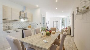 A modern kitchen with white cabinets, a wooden countertop, and a dining area with a wooden table and chairs. - Gorgeous home in Rosignano Marittimo with house a panoramic view (Rosignano Marittimo)
