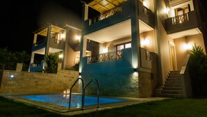 Un edificio de varios pisos con piscina, iluminación exterior y una escalera que lleva a los niveles superiores.