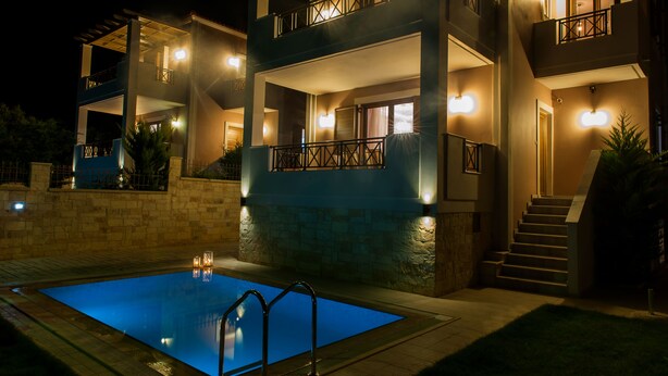 Un edificio moderno de dos pisos con piscina, iluminación exterior y una escalera que lleva a los niveles superiores.