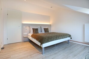 Une chambre moderne avec un lit, une table de chevet et un luminaire fixé au mur.