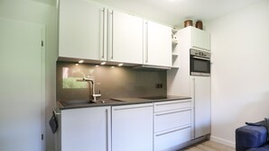 A compact kitchen with white cabinets, a stainless steel sink, a built-in oven, and a small countertop. - Vacationer village 43c, Germany (Ostseebad Boltenhagen)