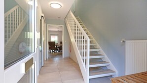 A staircase leading to a second floor, a dining area with chairs and a table, and a wooden bench. - Vacationer village 43c, Germany (Ostseebad Boltenhagen)