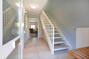 Un escalier menant à un deuxième étage, un coin repas avec des chaises et une table, et un banc en bois.