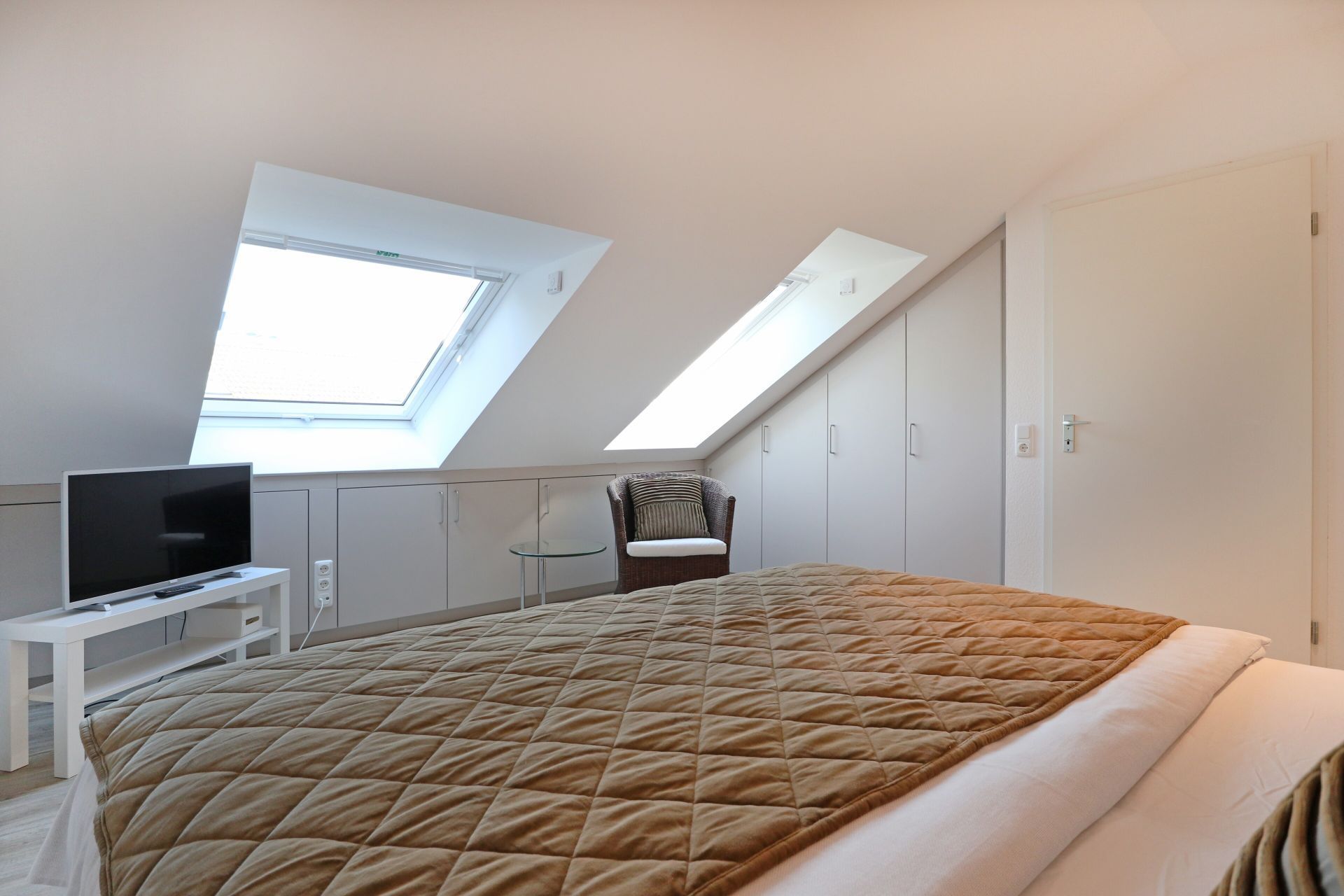 Een slaapkamer met een bed, een stoel, een televisie en een kledingkast.