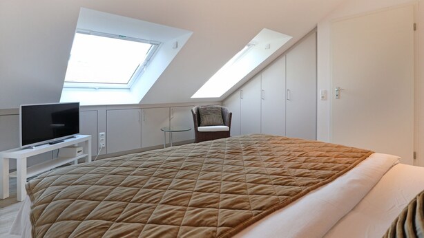 A bedroom with a bed, a chair, a TV, and a wardrobe. - Vacationer village 43c, Germany (Ostseebad Boltenhagen)