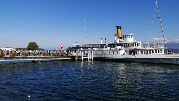 A large white boat docked at a pier with a clear blue sky in the background.