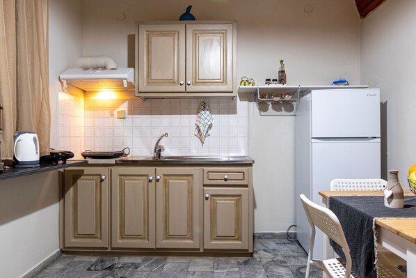 A kitchen with beige cabinets, a white refrigerator, and a small dining area with a table and chairs.