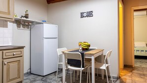 Una cucina funzionale con un frigorifero bianco, un tavolo da pranzo con quattro sedie e un cartello con la scritta 'HOME'.