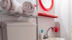A bathroom with a toilet, sink, and a shelf with towels.