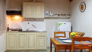 A kitchen with cream-colored cabinets, a white refrigerator, and a dining table with chairs.