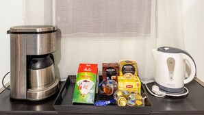 Kahvinkeitin, vedenkeitin sekä erilaisia kahvi- ja teetuotteita tarjottimella.