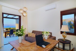 Uma sala de estar moderna com um laptop sobre uma mesa de madeira, um sofá, uma mesa de centro e uma luminária. Há uma janela com vista para o exterior.