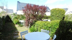 Eine Holzterrasse mit einem runden Tisch und vier Stühlen.