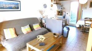 Ein gemütliches Wohnzimmer mit einer grauen Couch, einem Holztisch und einem Essbereich mit Tisch und Stühlen.