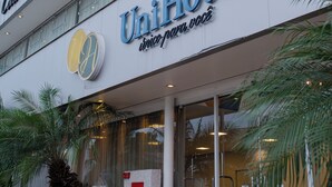 Un hotel con fachada moderna, señalización que indica 'Cabriel Flat' y 'UniHotel', y entrada de vidrio.