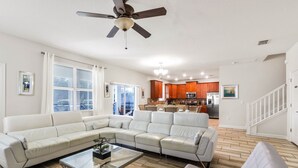 A spacious living room with a sectional sofa, a glass coffee table, and a ceiling fan. - South-Facing Pool & Spa • No Rear Neighbors • Game Room • Near Disney (Davenport)