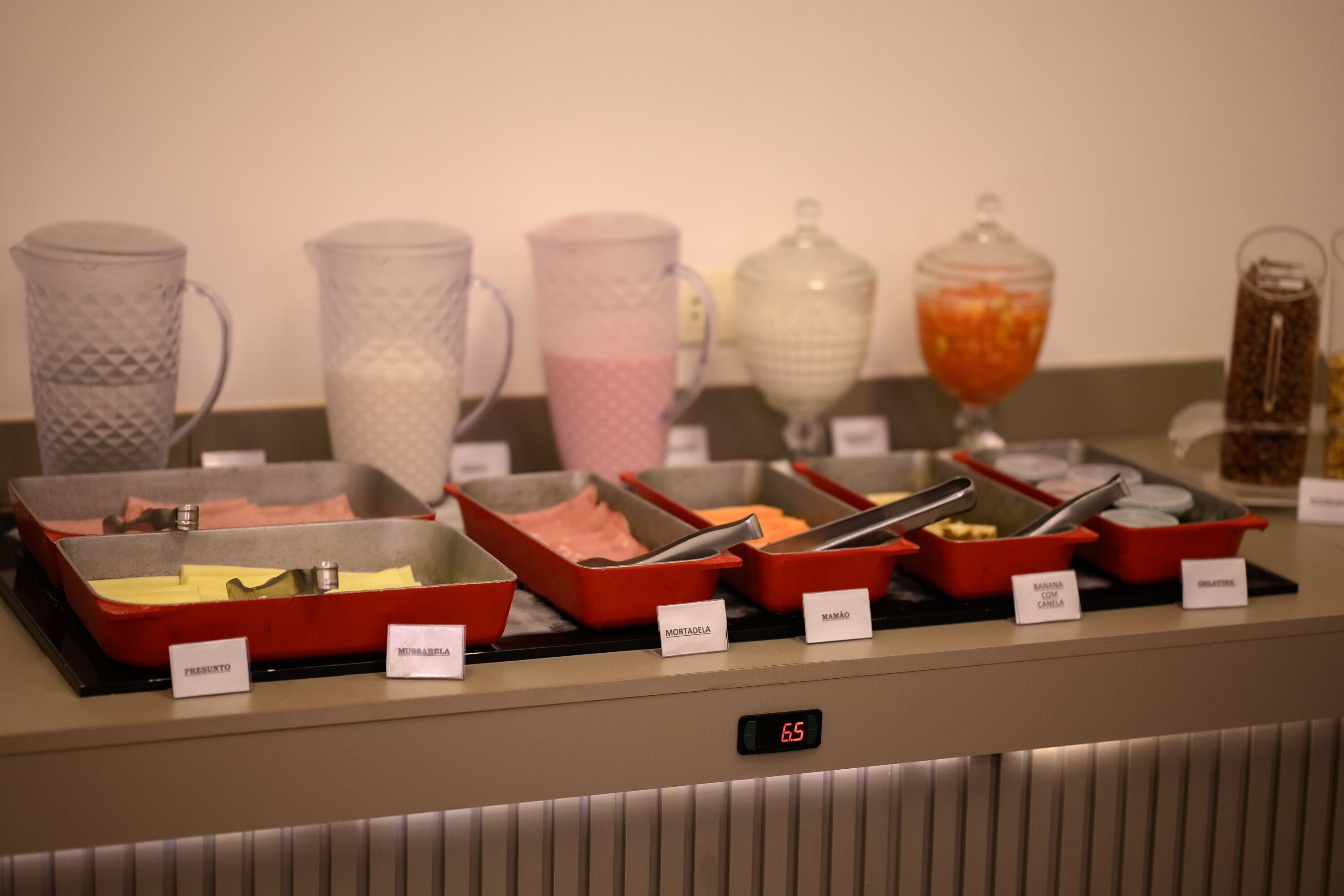 A buffet with labeled food items and a digital clock displaying 6:55.
