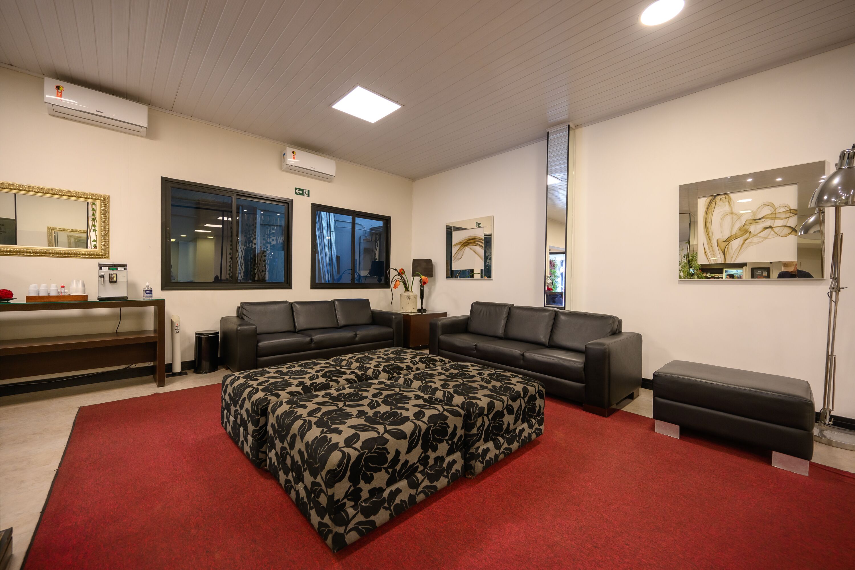 Quarto moderno com sofá modular, tapete vermelho e um espelho grande.