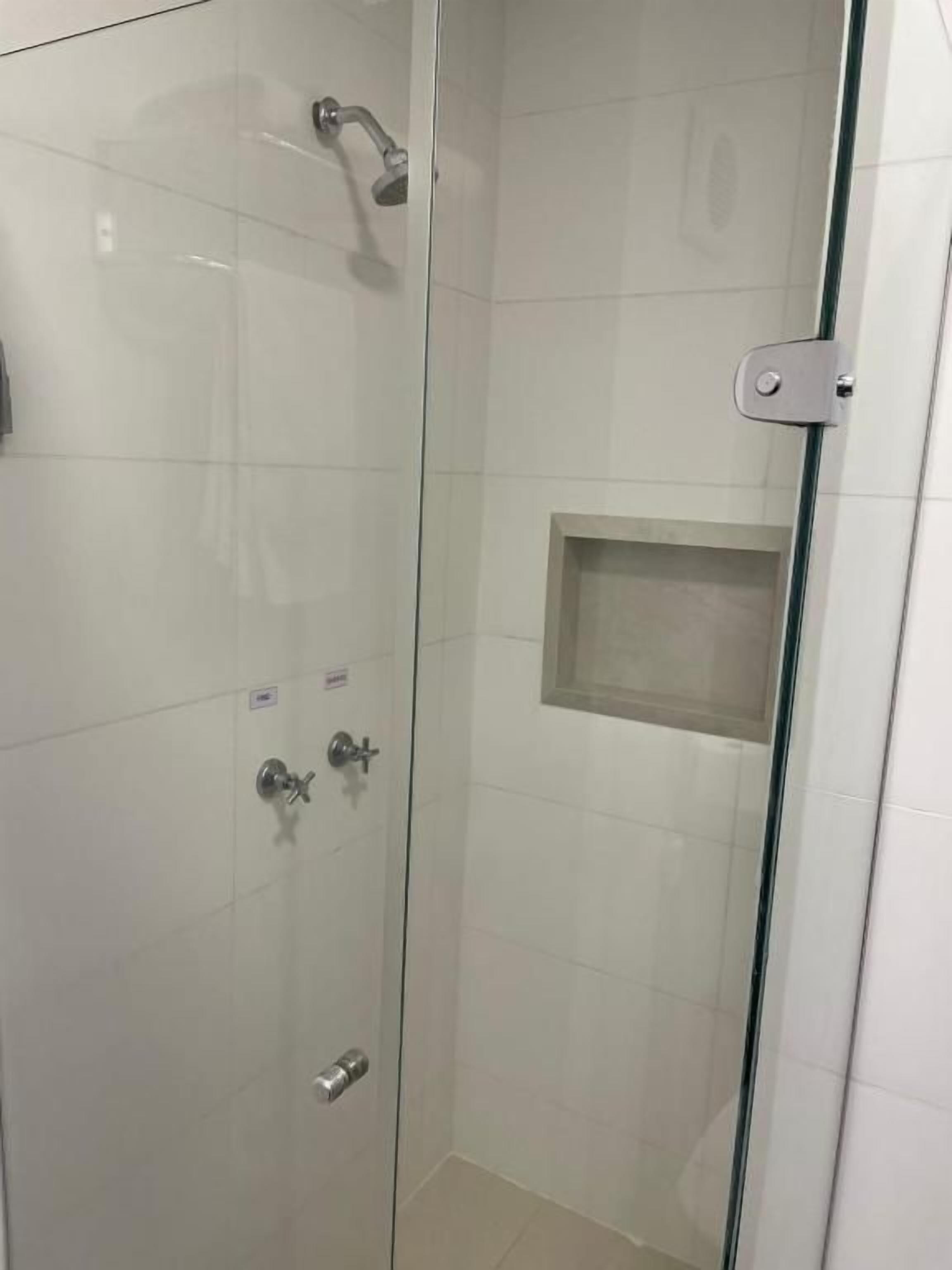 A glass-enclosed shower stall with a handheld showerhead and a wall-mounted faucet.