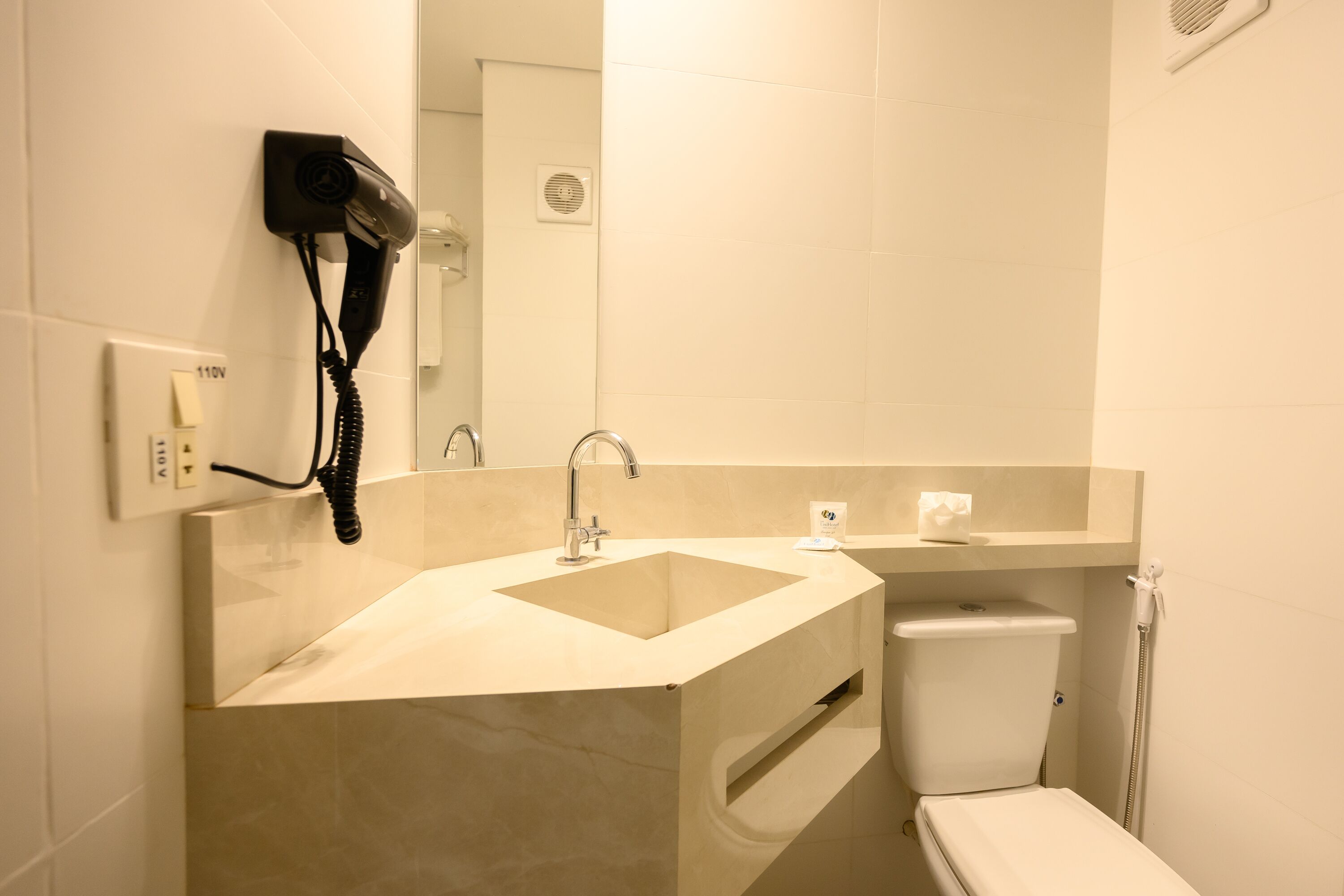 A modern bathroom with a sink, mirror, and toilet.