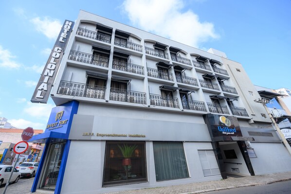 Un hotel de varios pisos con balcones, un cartel que dice 'Hotel Colonial' y un cartel que indica 'Unihotel'.